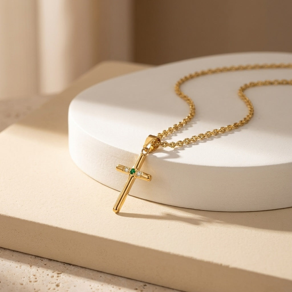 Gold-tone chain and cross pendant arranged diagonally on a cream display surface.