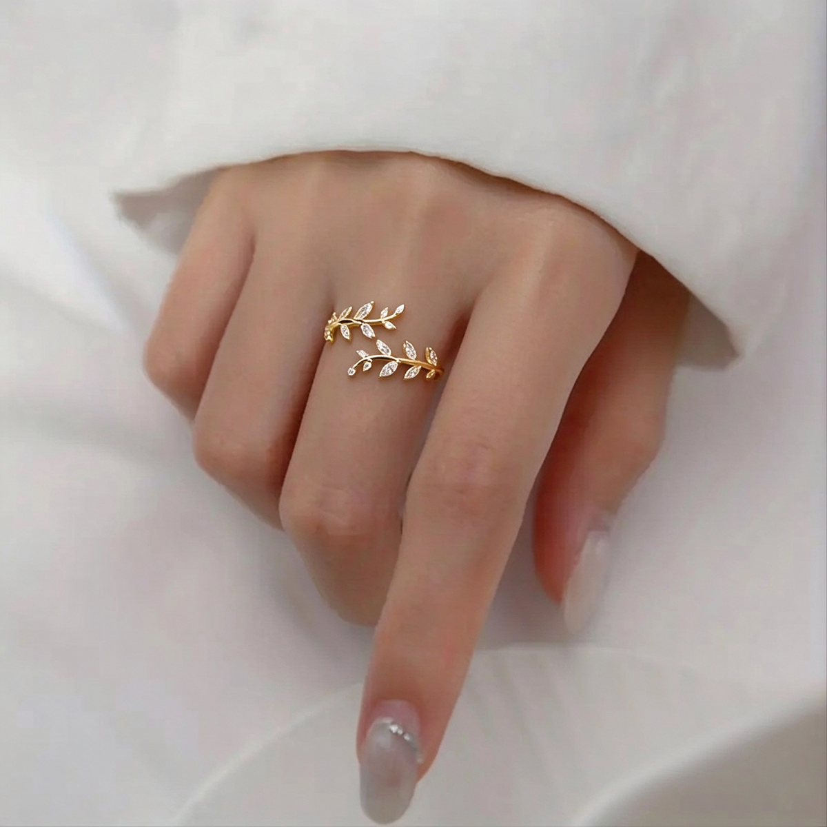 Close-up of a hand wearing the gold-tone leaf vine ring, showing its delicate botanical design.