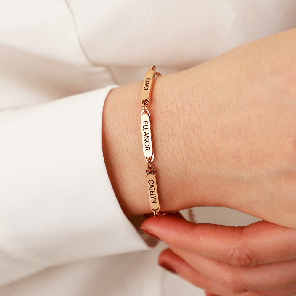 Name bar bracelet worn around a wrist, showing the slim linked design and engraved plate details.