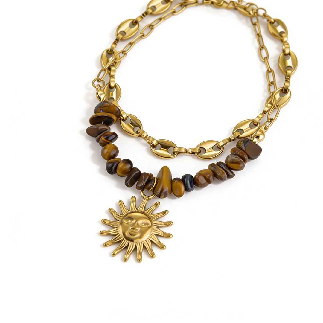Detailed texture of the double-layered chain and polished sun charm on a gold flower bracelet.