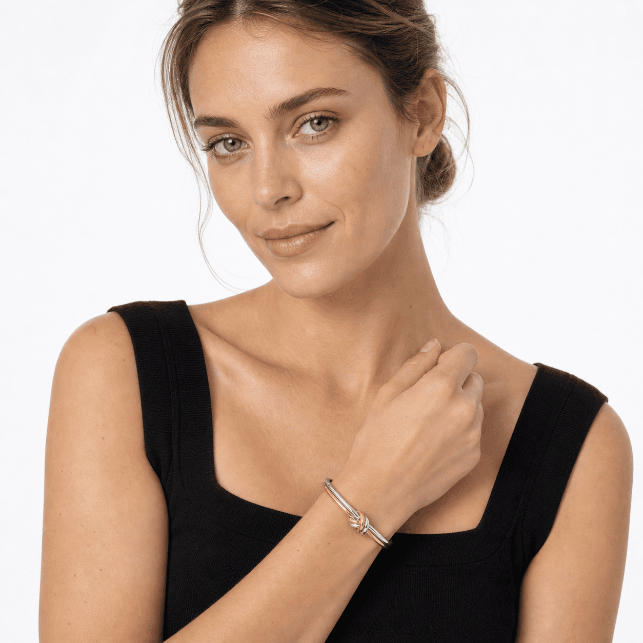 Woman wearing a mixed-metal double-strand knot cuff bracelet in a white-studio portrait