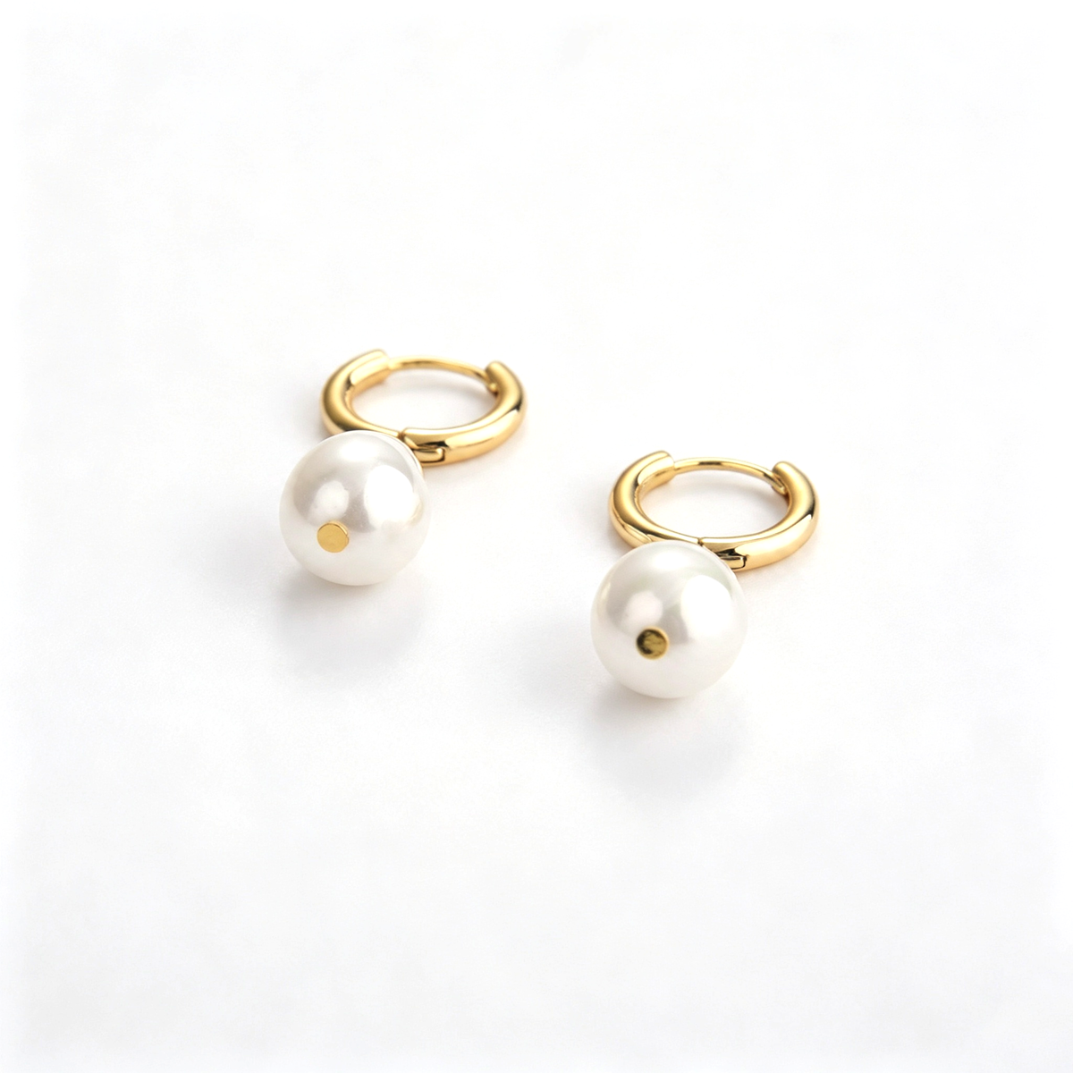 Close-up of drop hoop earrings showing the round hoops and teardrop accents