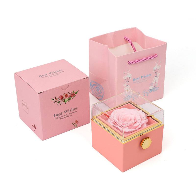 Pink rotating rose jewelry box with clear lid, matching packaging and gift bag.