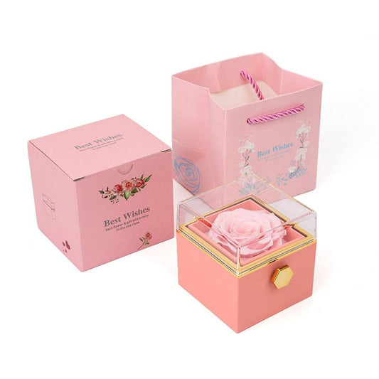 Pink rotating rose jewelry box with clear lid, matching packaging and gift bag.