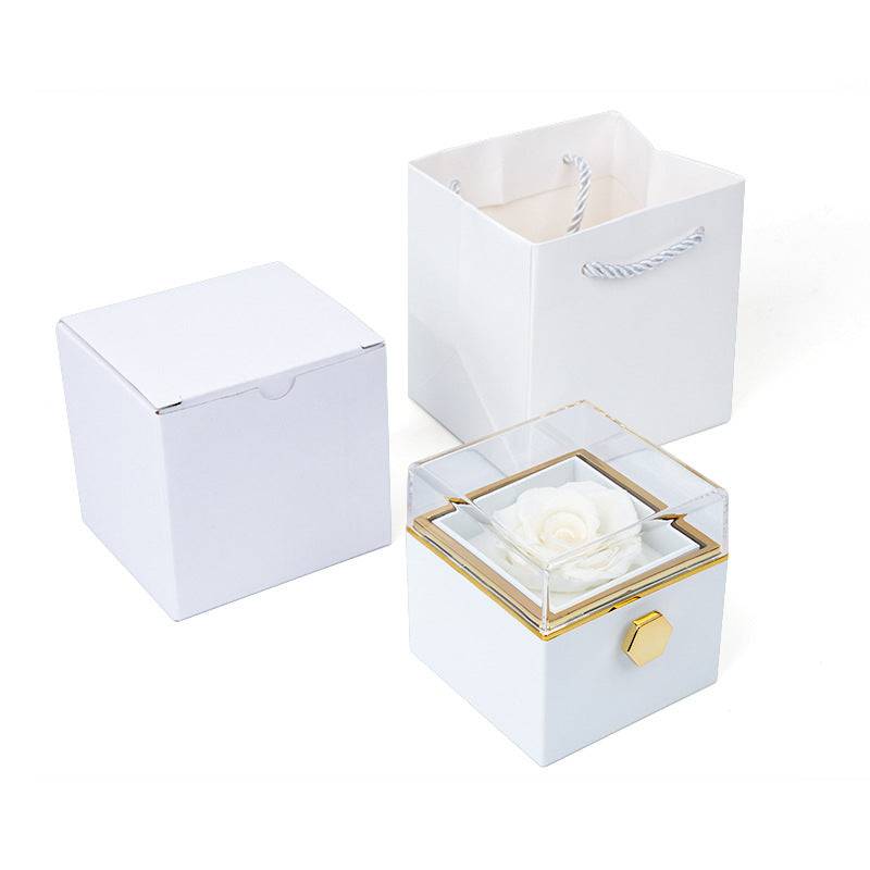 White rotating rose jewelry box with clear lid and white rose, shown with matching packaging.