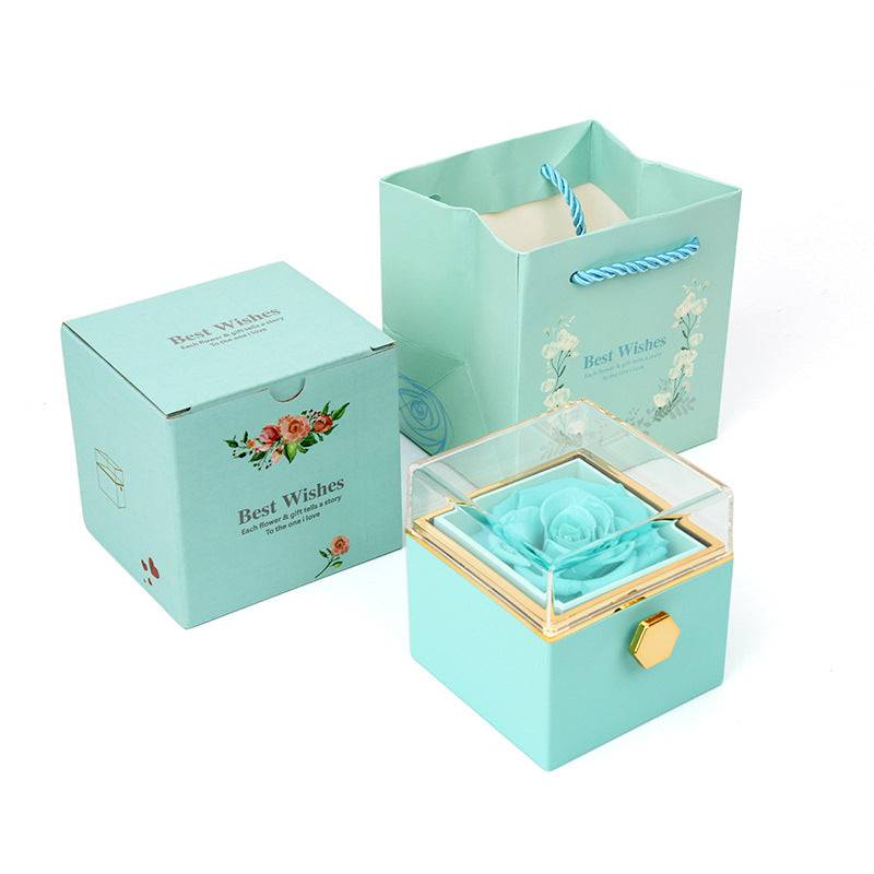 Mint rotating rose jewelry box with clear lid and blue rose, shown with matching packaging.