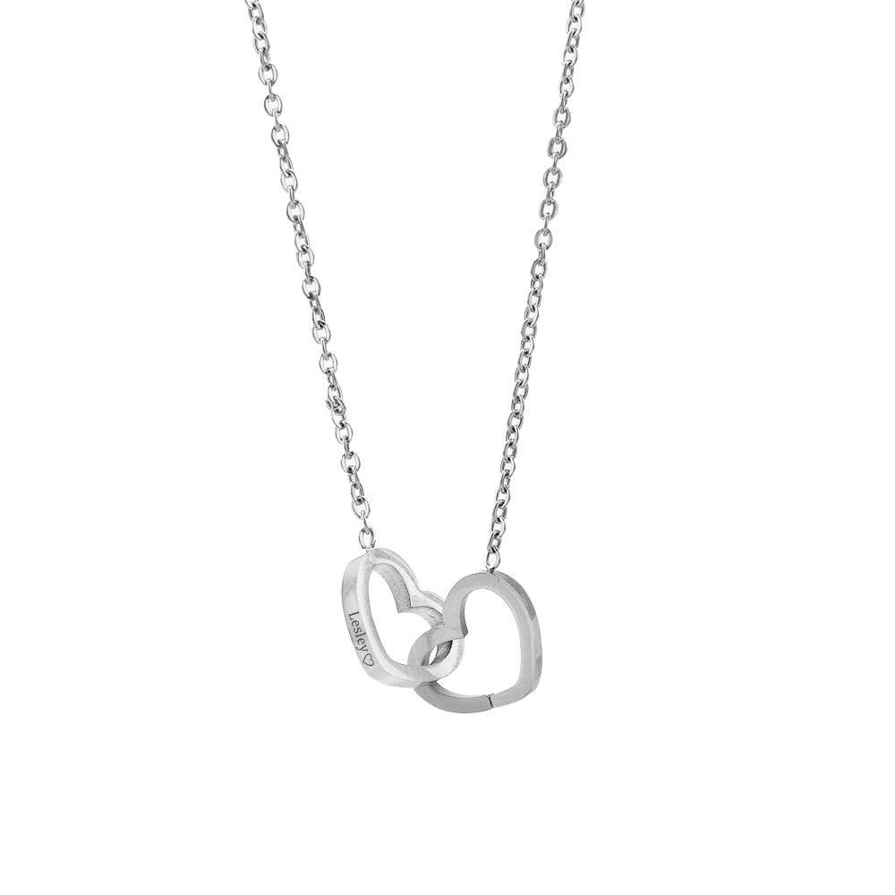 Silver-tone engraved double heart necklace hanging against a white background.
