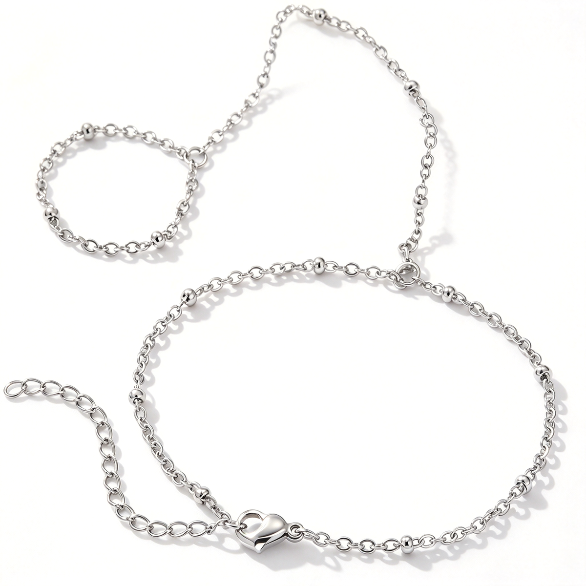 Silver-tone chain hand bracelet with a heart charm and small round bead accents displayed on a white background.