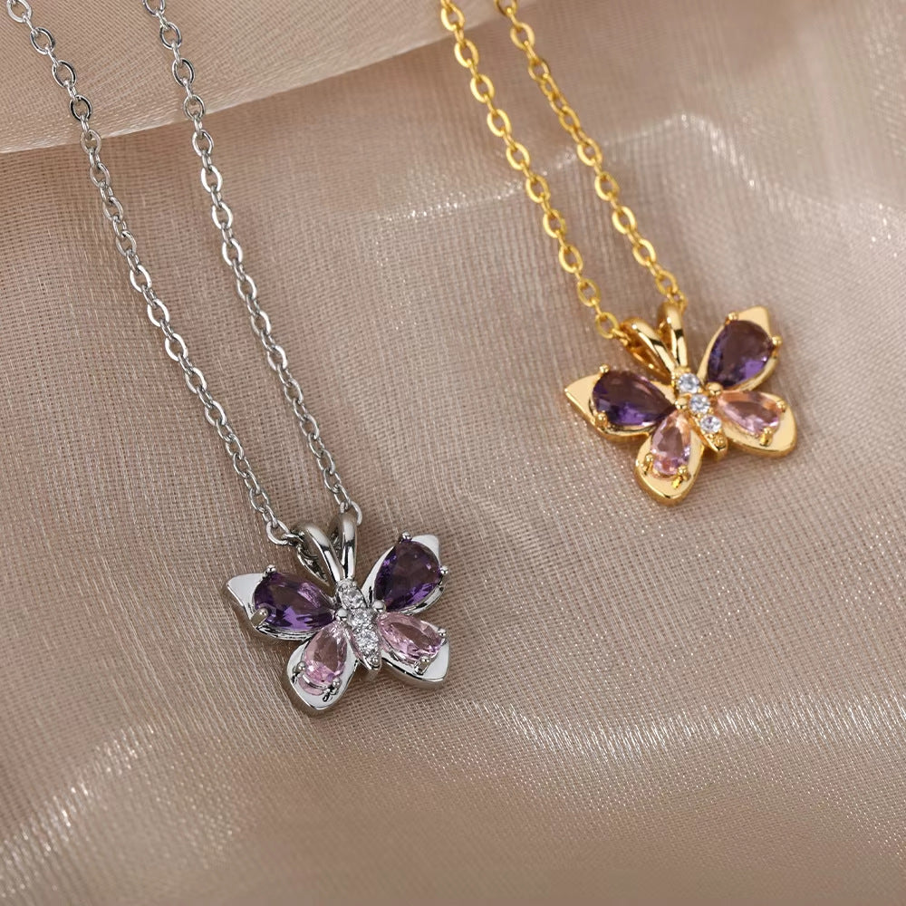 Gold-tone and silver-tone butterfly pendant necklaces arranged on textured beige fabric