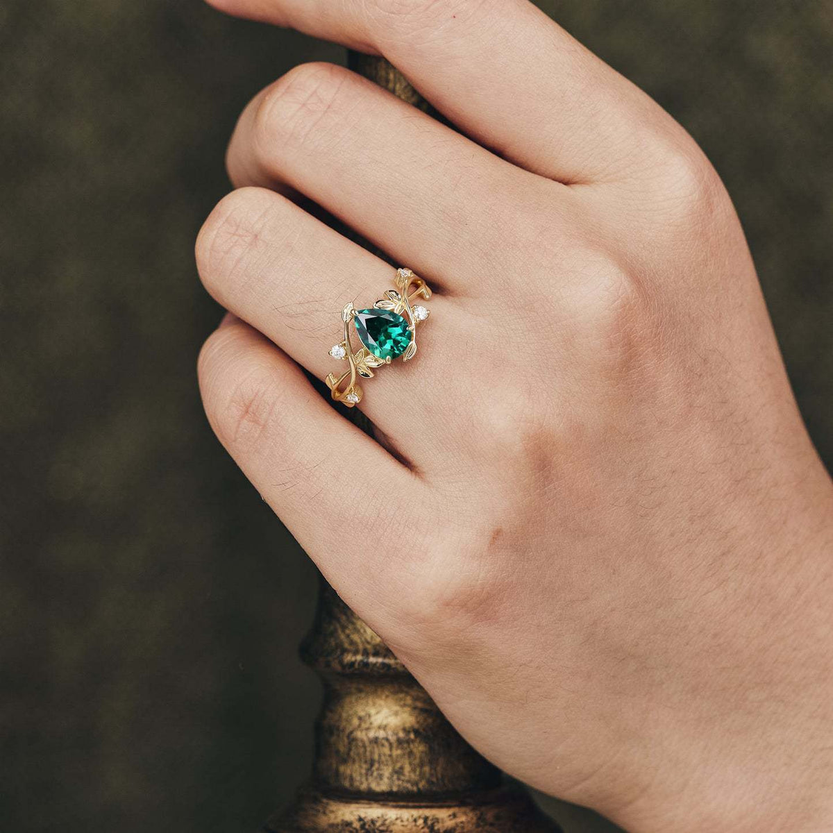 Emerald green teardrop ring worn on a hand, showing how the statement design looks when styled with an outfit.