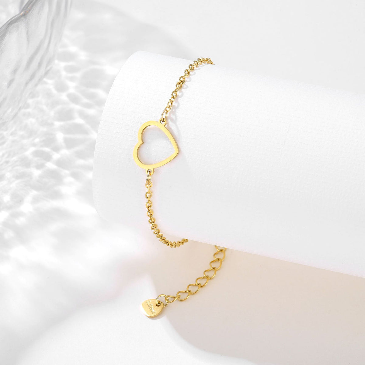 Gold-tone heart bracelet displayed on a white jewelry stand for a closer view of its delicate design