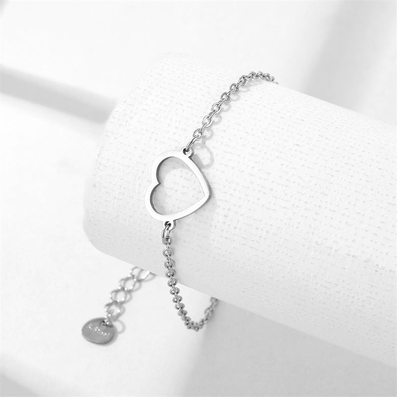 Silver heart bracelet displayed on a white jewelry stand, highlighting the heart-shaped centerpiece