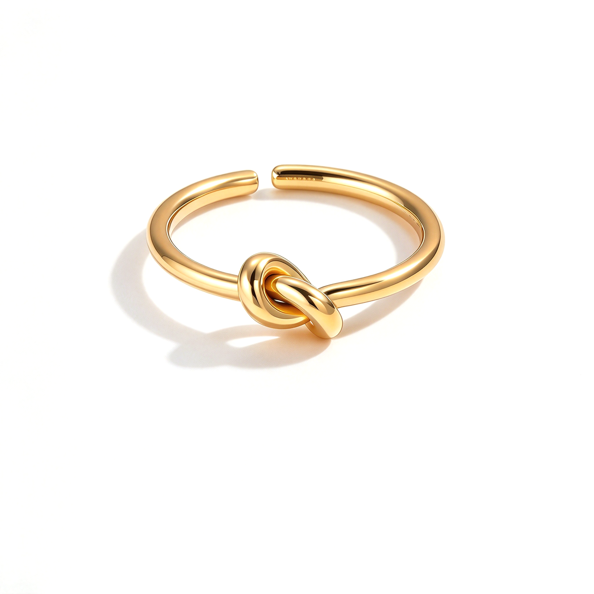 Gold-tone knot open ring with a smooth curved band displayed on a white background.