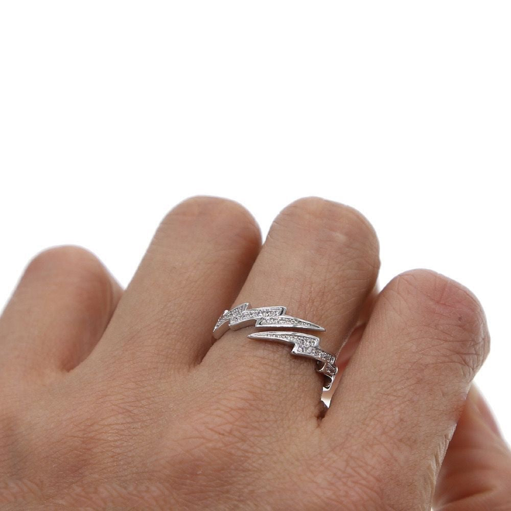 Close-up of a lightning bolt ring worn on a finger, showing its angular design and sparkling details.