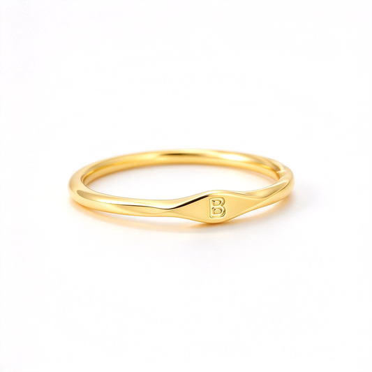 Minimalist initial ring with a slim band and small letter detail, shown on a white background.