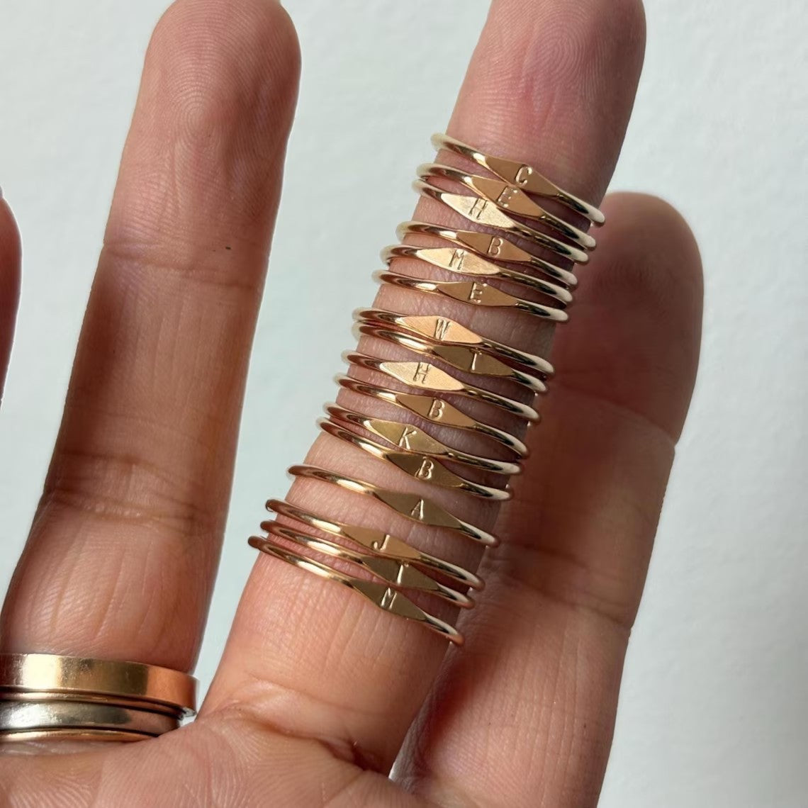 Several slim rings stacked along a finger beside a simple band ring, showing a layered styling option.