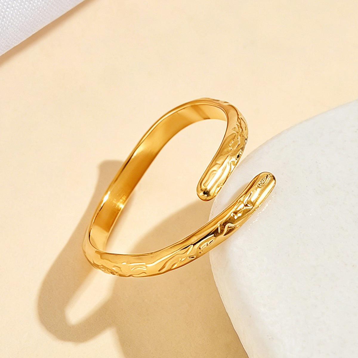 Close-up of a gold-tone open ring highlighting its curved shape and textured surface