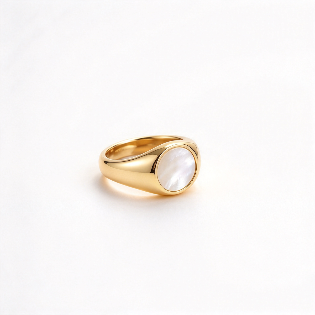 Gold-tone oval ring displayed at a low angle, showing its rounded centerpiece and curved band.