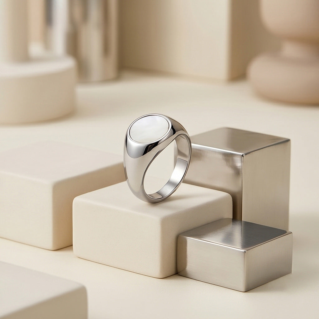 Silver-tone oval ring displayed upright on a cream jewelry box, highlighting its raised face and broad band.