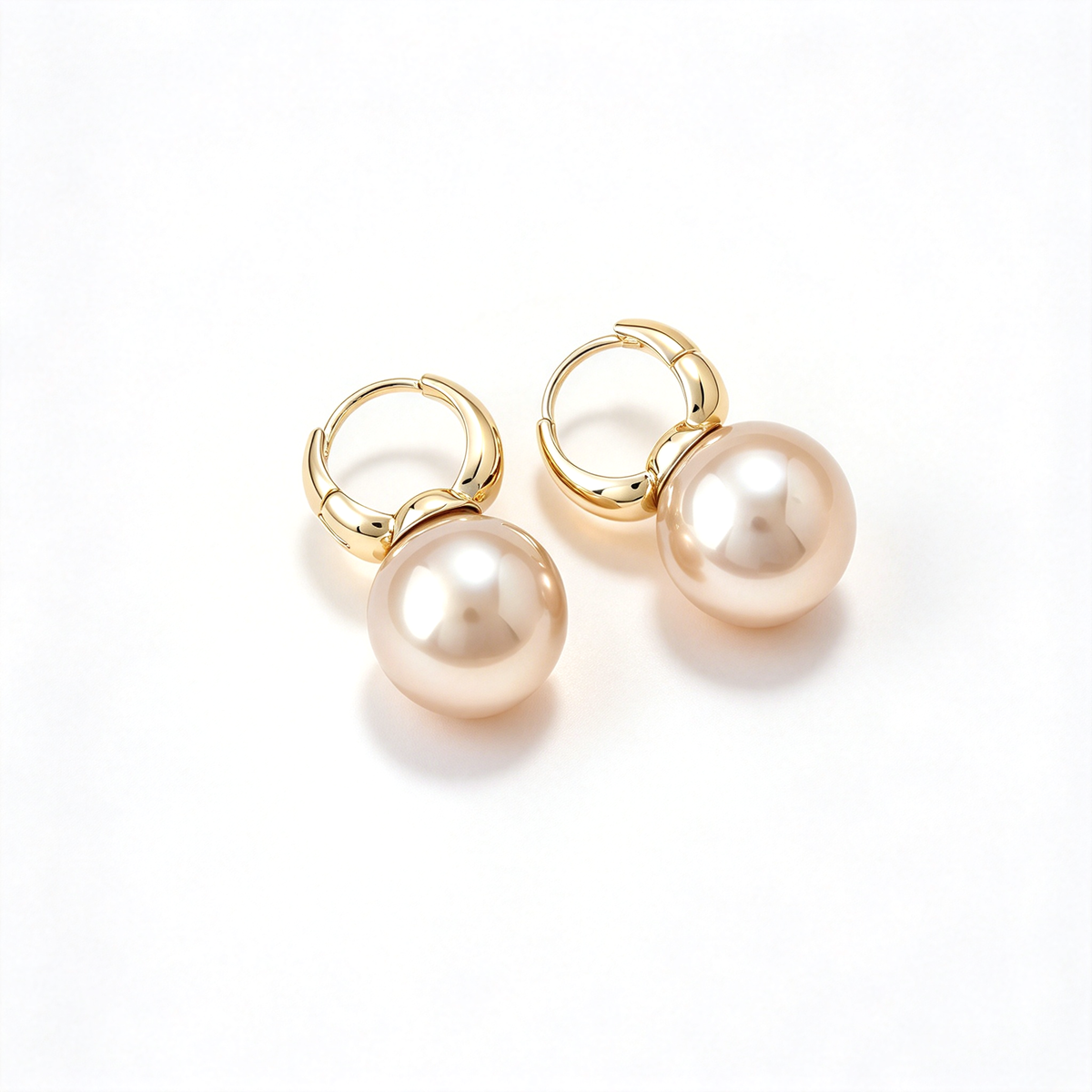 A pair of pearl drop hoop earrings displayed against a clean white background.