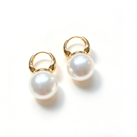 Angled view highlighting the curved hoop closures and round dangling accents on both earrings.