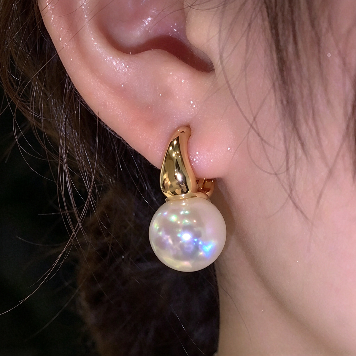 Pearl drop hoop earring shown worn on the ear, highlighting the rounded dangling accent and elegant profile.