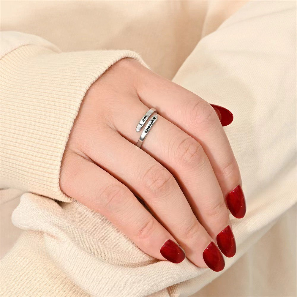 Open cuff ring with engraved message shown on a hand against a cream background