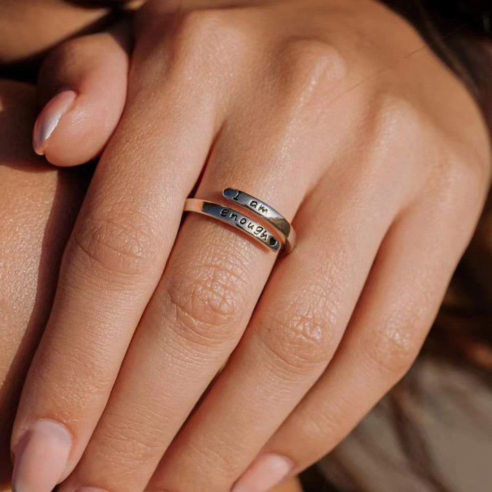 Close-up of the open ring's curved bands and dark lettering worn on a finger