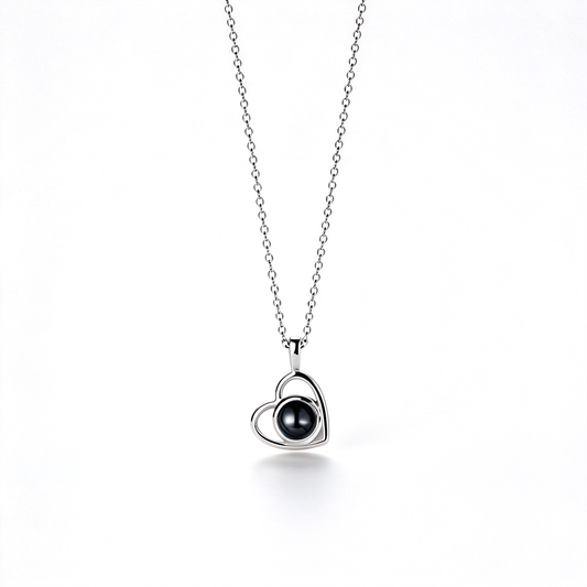 Silver-tone heart pendant with a glossy dark center, shown hanging from a fine chain against a white background.