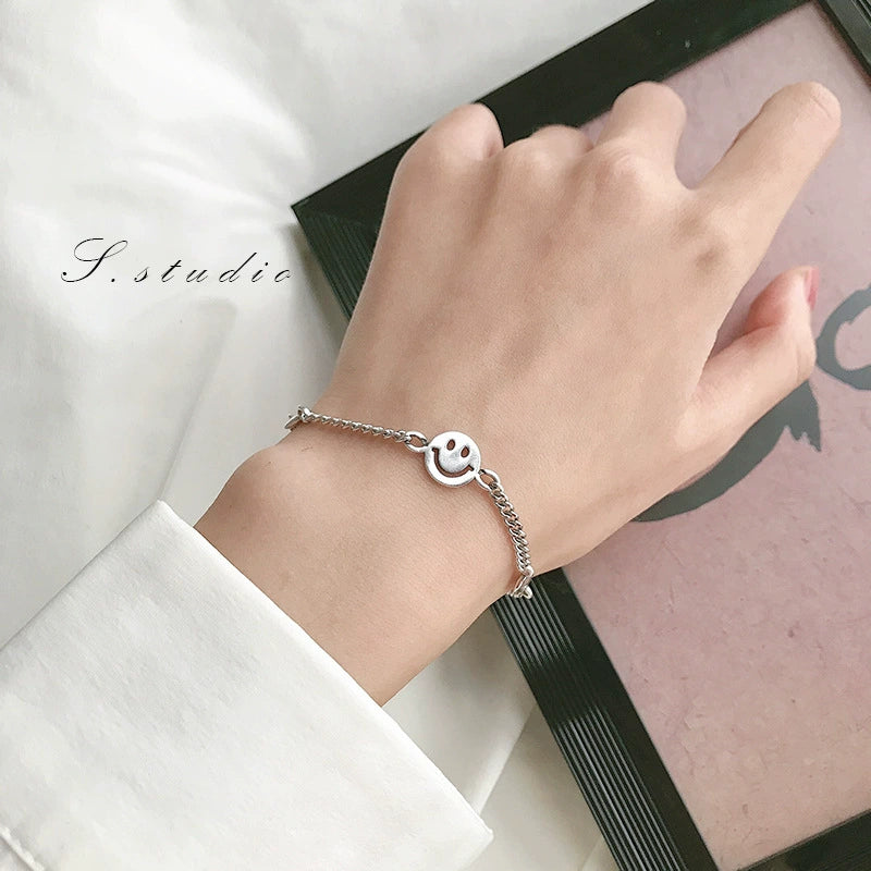 Round smiley face charm and linked chain shown on a wrist for a closer look at the bracelet design.
