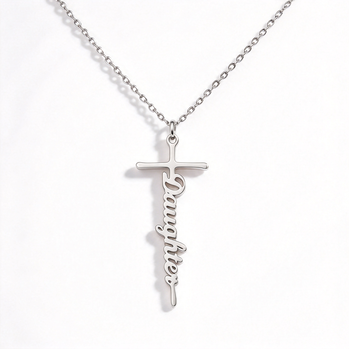 Straight-on view of a cross-shaped word pendant suspended from a fine-link necklace chain.