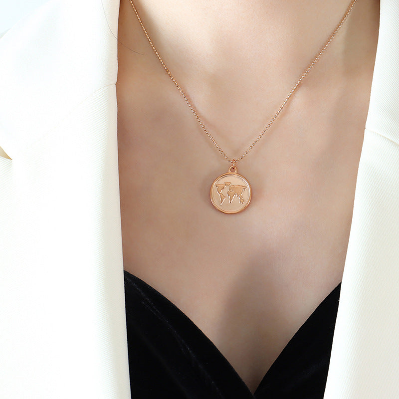 Rose gold-tone world map pendant necklace worn with a black V-neck top.