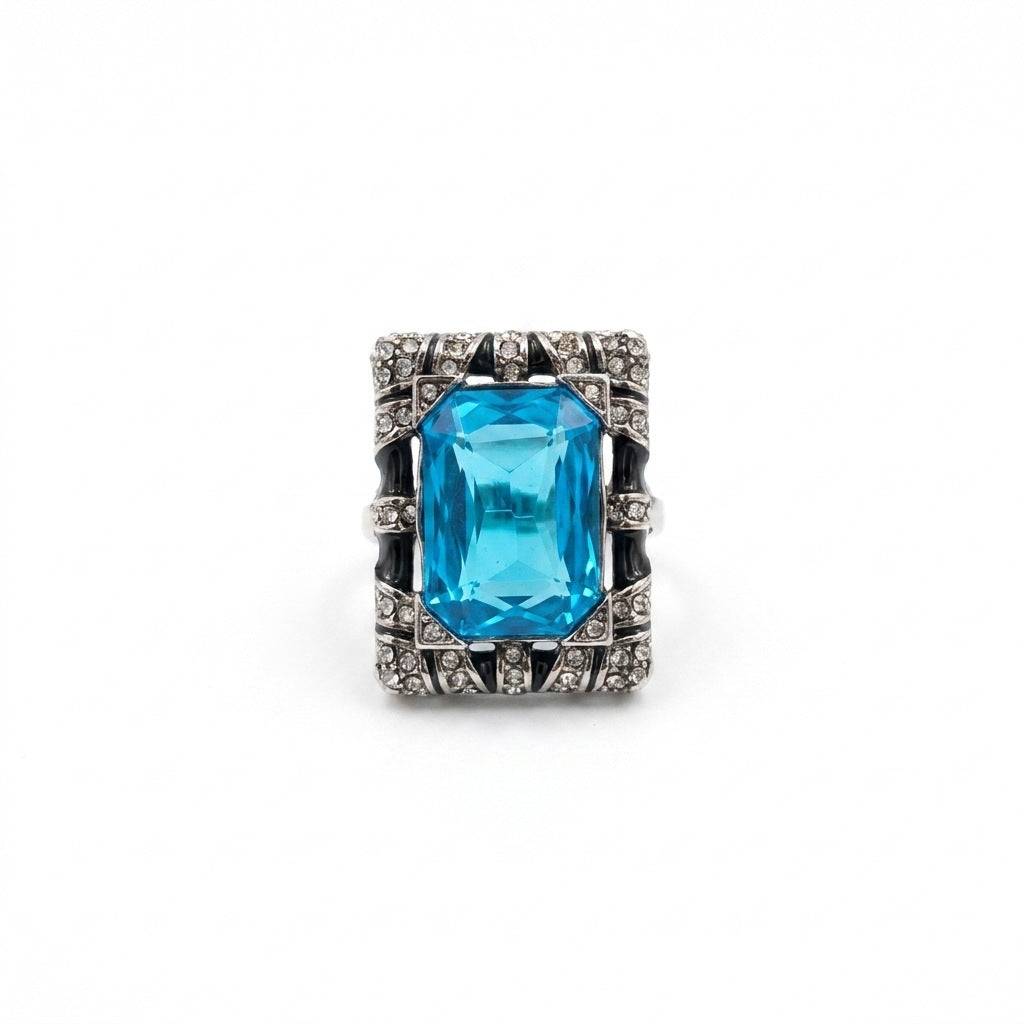 Adjustable gold ring with a large blue aquamarine-style stone and pearl accents.