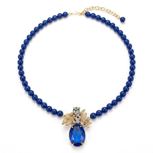 Large blue rhinestone pendant on a gold snake chain necklace, vintage style.