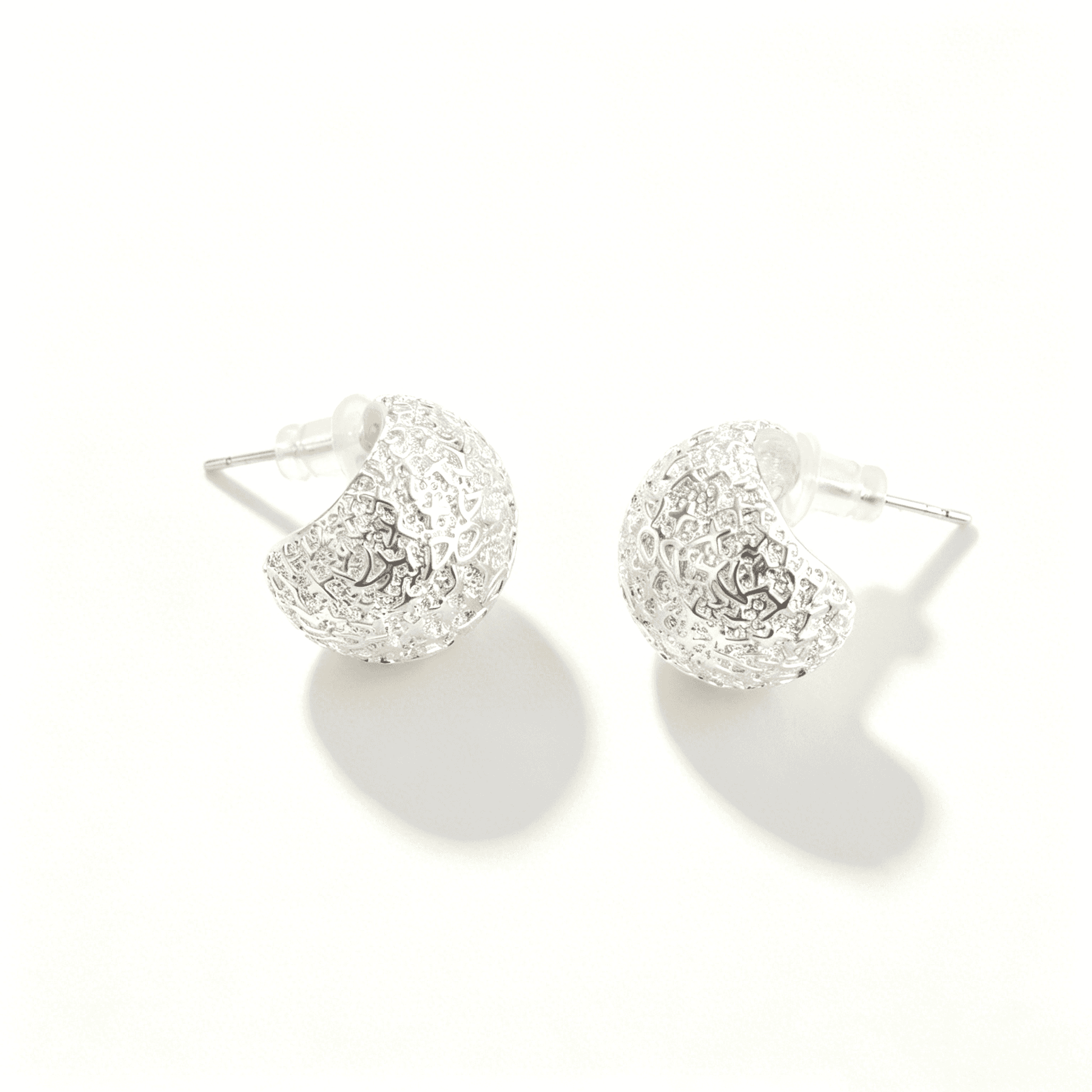 Side view of Ever P. chunky silver hoops, highlighting the unique light-reflecting hammered surface.