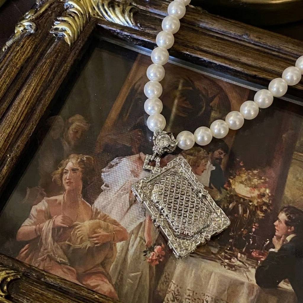 Close-up of the emerald-cut aquamarine stone on a vintage-style gold necklace.