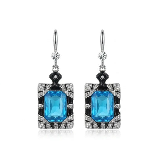 Elegant geometric drop earrings featuring blue aquamarine crystals and white pearls.