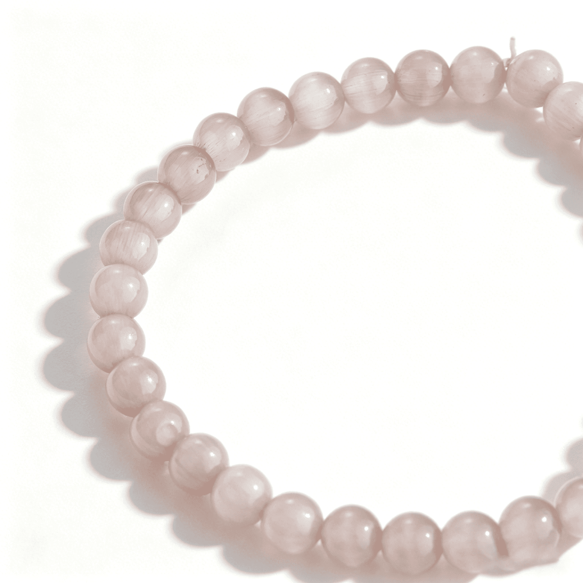 A detailed view of the handmade crimson crystal bracelet with a soft peach-pink glow.
