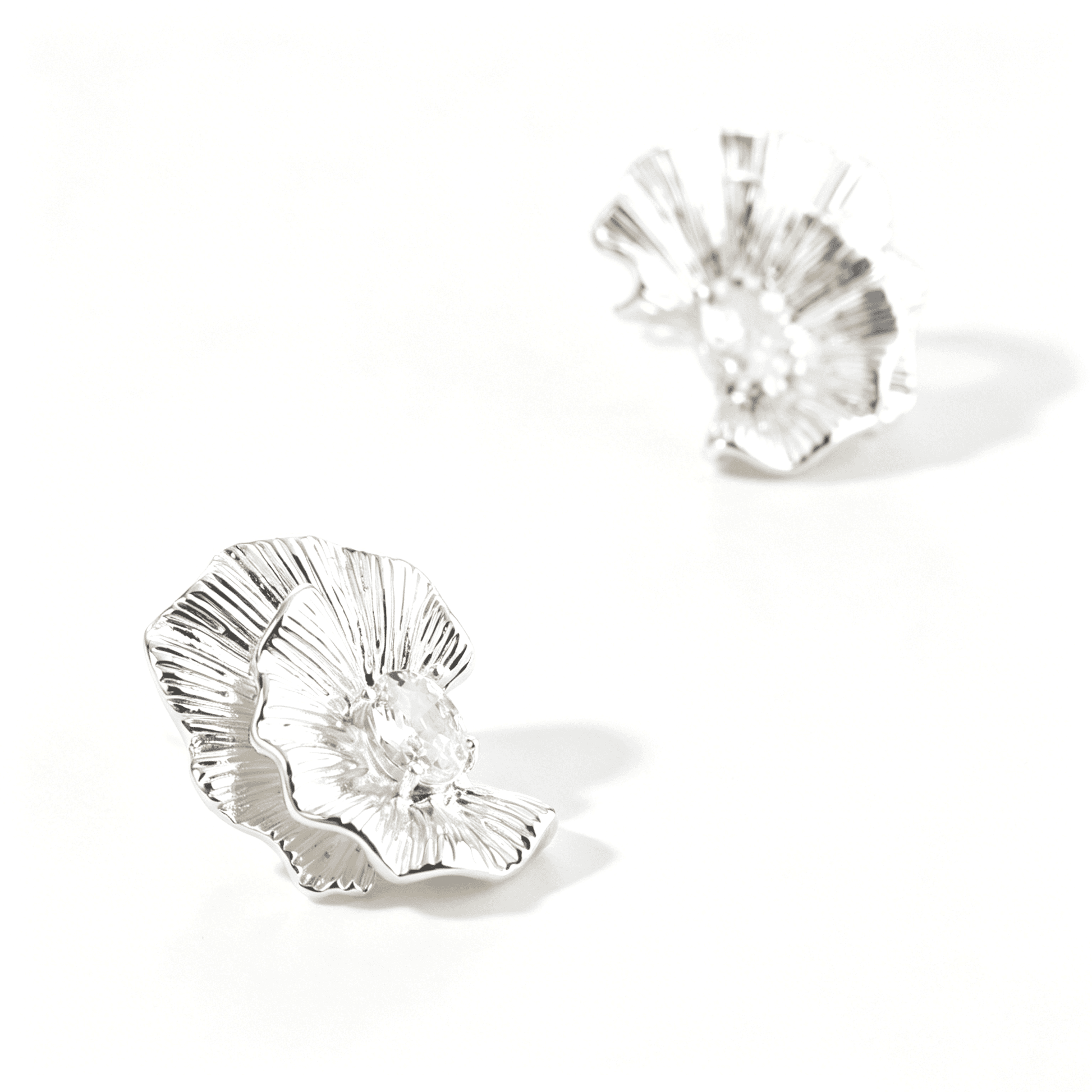 Ever P. modernist silver flower earrings presented in a minimalist jewelry setting.