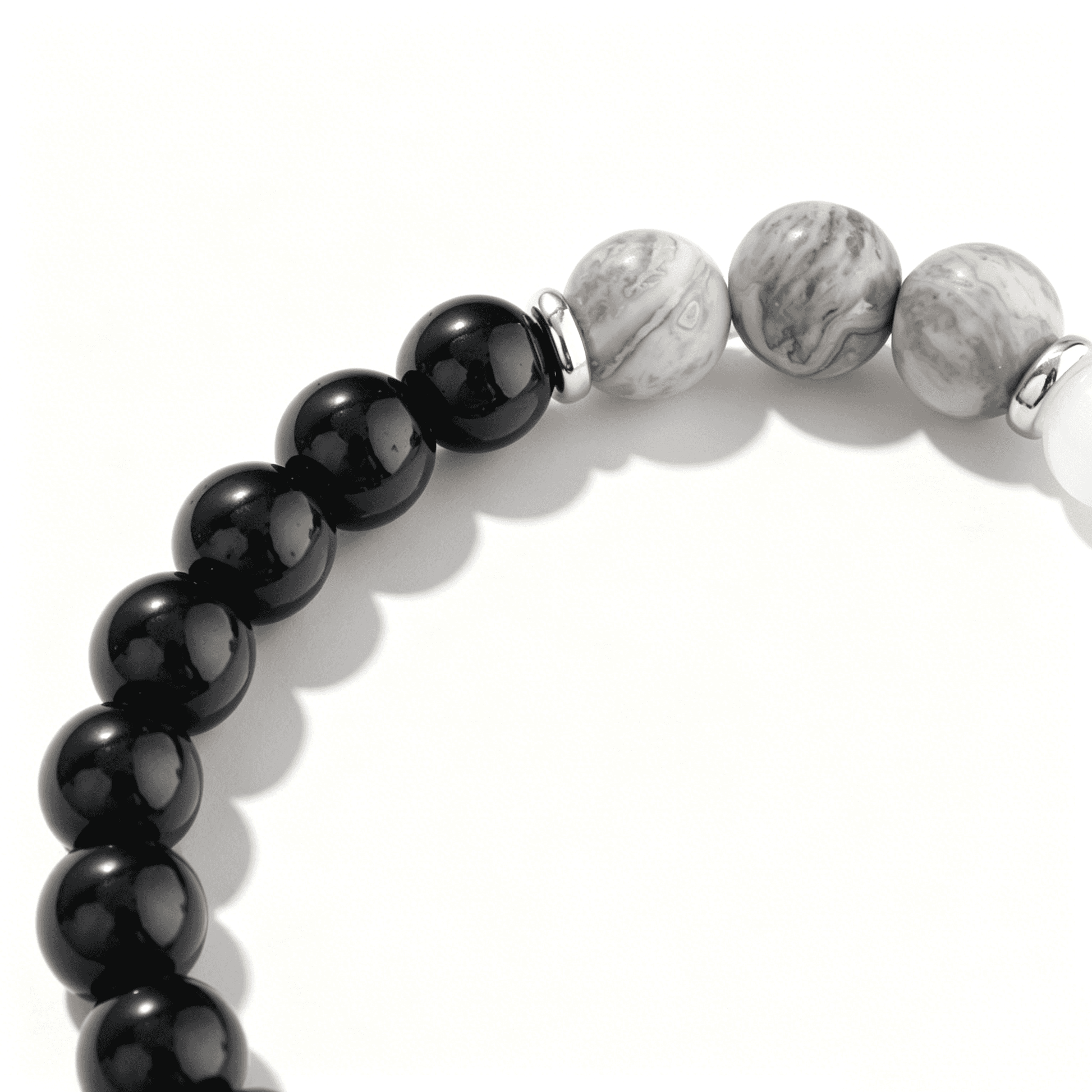 Close-up of glossy black beads transitioning to detailed grey marble stone beads in an Ever P. monochrome bracelet.