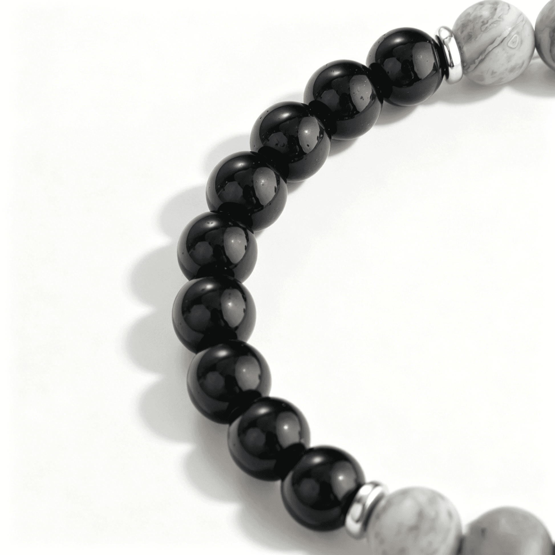 Close-up detail of smooth, high-gloss black onyx beads and silver metal spacers in an Ever P. monochrome bracelet.