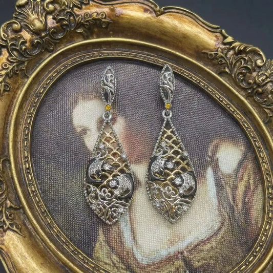 Detailed view of the fish scale hollow-out pattern on Ever P. gold drop earrings.
