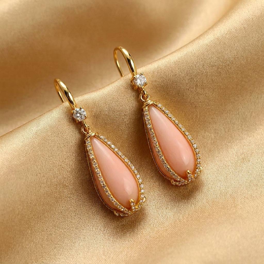 Detailed view of the French hook on the pastel pink drop earrings with an antique gold finish.