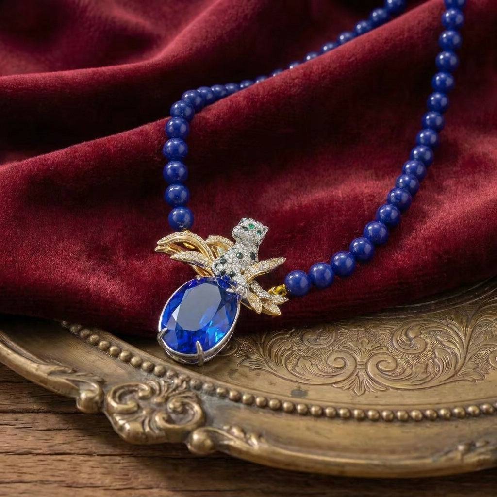 Detail view of the 18K gold snake chain jewelry with a sapphire-hue pendant.