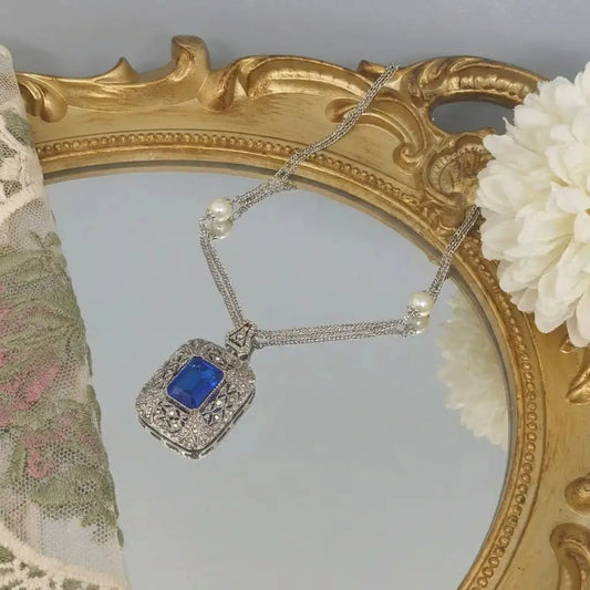 Detailed view of the Victorian style jewelry pendant featuring a sapphire-hue stone.