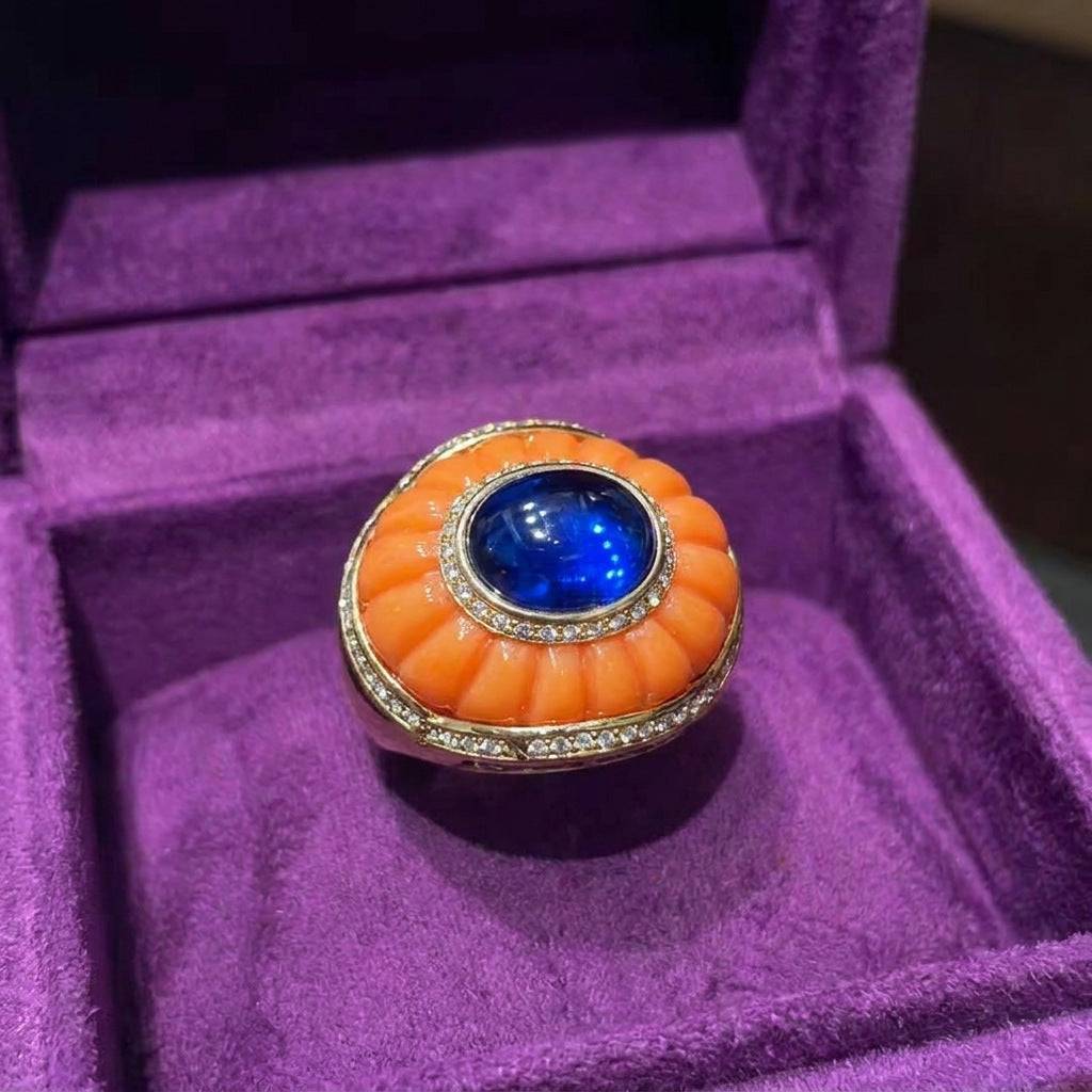 Overhead product shot comparing the cobalt blue and burnt orange cocktail ring versions, highlighting the adjustable open-band geometry.