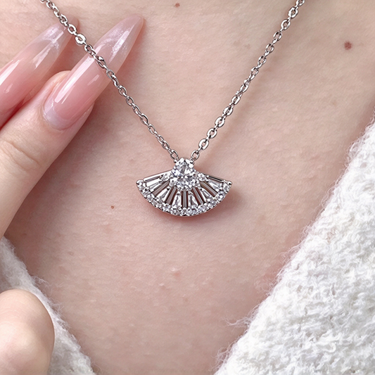 Fan-shaped pendant necklace worn at the neckline, highlighting its delicate chain and sparkling radiating design.