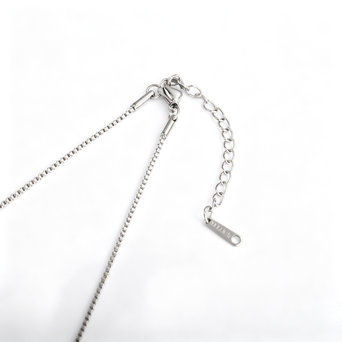 Close-up view of a silver-tone lobster clasp, extender chain, and tag on a box chain.