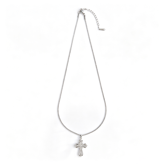 Full view of a silver-tone filigree cross pendant necklace laid flat on a white background.