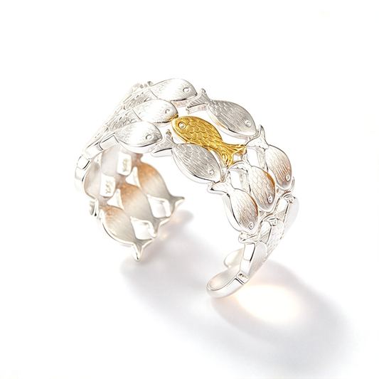 Angled view of a fish school ring showing its curved open band and layered fish-shaped design